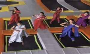 Group of women in traditional attire dancing on trampolines in a vibrant indoor setting, showcasing energy and joy.